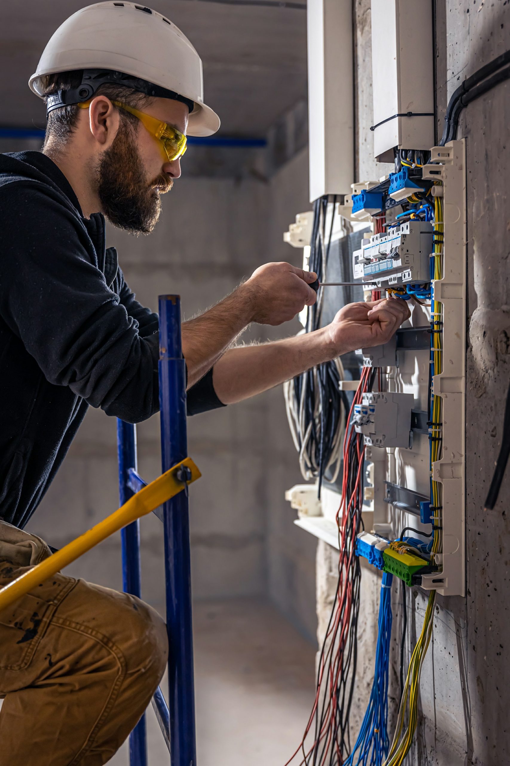 Male electrician works switchboard with electrical connecting cable1 scaled
